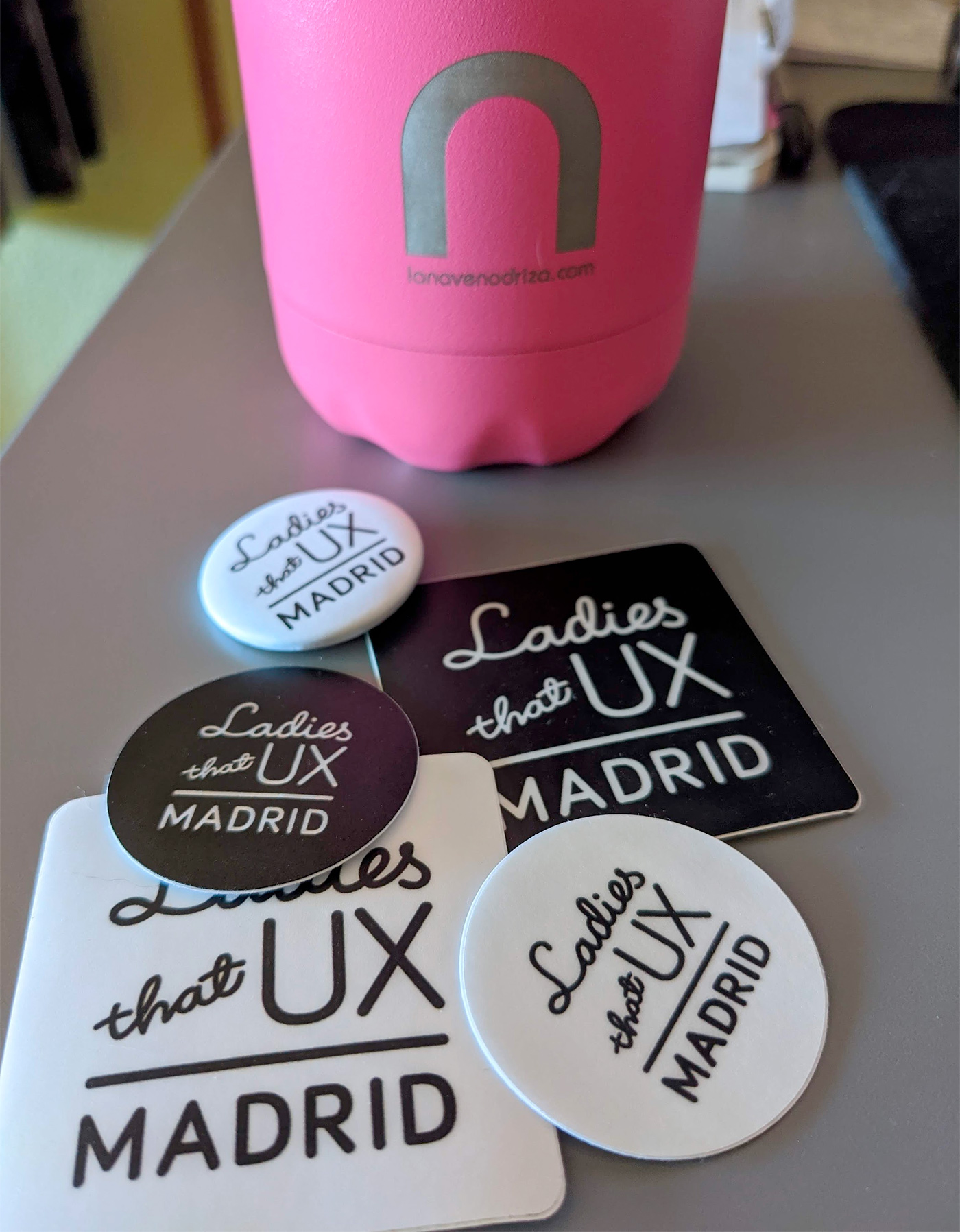 La botella de La Nave Nodriza y chapas y pegatinas de Ladies that UX Madrid